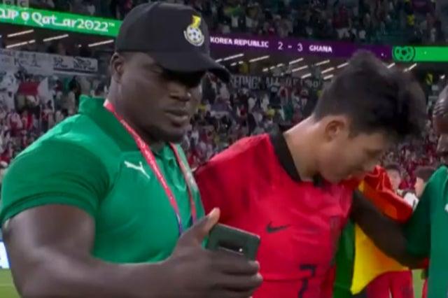 A Ghana staff member takes selfie with despondent Heung-min Son after victory over South Korea