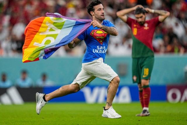 A pitch invader runs across the field with a rainbow flag during the World Cup group H match between Portugal and Uruguay, at the Lusail Stadium in Lusail