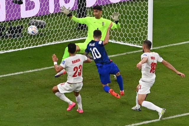 USA’s forward #10 Christian Pulisic scores his team’s first goal past Iran’s goalkeeper #01 Alireza Beiranvand during the Qatar 2022 World Cup Group B football match between Iran and USA at the Al-Thumama Stadium in Doha